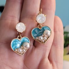 Introducing our beautiful beach-themed dangle earrings, perfect for those who love to feel the sand between their toes and the salty breeze in their hair. These earrings feature a heart-shaped dangle design with ocean blue enamel and pearl finish details, creating a stunning and serene look. Crafted with care and attention to detail, these earrings feature a secure lever back closure that ensures they stay comfortably in place all day long. The heart-shaped dangle design adds a touch of romance and femininity to the earrings, while the ocean blue enamel and pearl finish details create a serene and calming effect. The focal point of these earrings is an 8mm opal pearl cabochon that adds a touch of natural beauty and texture to the design. The opal pearl cabochon reflects the light in a mesm Ocean Earrings, Aqua Earrings, Orange Necklace, Iridescent Pearl, Retro Earring, Heart Dangle Earrings, Holiday Earring, Valentines Jewelry, Enamel Earrings