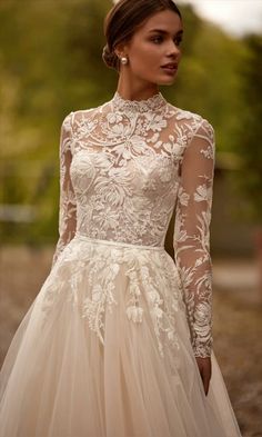 a woman wearing a wedding dress with long sleeves and a high neckline is posing for the camera