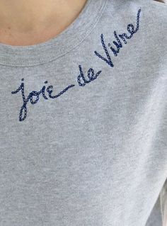 a woman wearing a grey shirt with blue writing on it