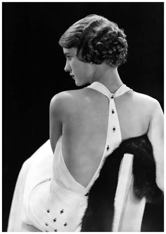 black and white photograph of a woman sitting on a chair with her back to the camera