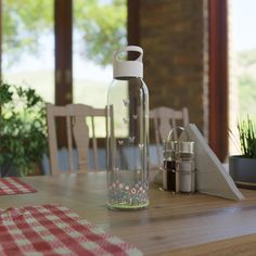 a glass water bottle sitting on top of a wooden table