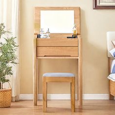 a bedroom with a bed, mirror and stool in it next to a potted plant