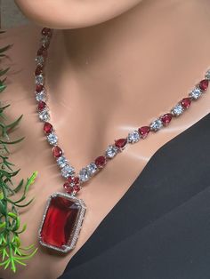 This stunning Bollywood-inspired jewelry American diamond  necklace  set is perfect for any special occasion. The set includes a beautiful silver plated  finish with lab created ruby red color stone with  long  pair of earrings, both adorned with intricately detailed ruby  color  stones. The jewelry is handmade in India with silver  plating on a brass base metal.  This trendy jewelry set is a true work of art and features adjustable features for your convenience. It is perfect for engagement, we American Diamond Necklace Set, Ruby Red Color, Ruby Color, American Diamond Necklaces, Anniversary Event, Diamond Necklace Set, Color Stones, Color Stone, Inspired Jewelry