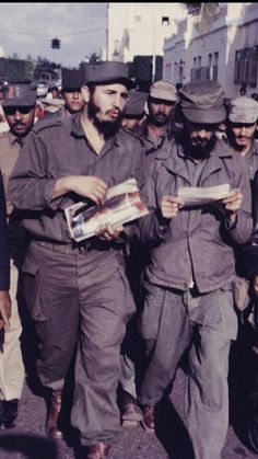 a group of men walking down a street next to each other with newspapers in their hands