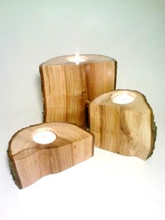 three wooden candle holders with candles in them on a white surface and one is made out of wood