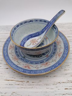 two blue and white plates with gold trimmings on them, one has a spoon in it