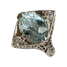 This is a stunning antique Art Deco 2.6 Carat Aquamarine and Old Mine Cut Diamond Ring in an 18 Karat White Gold filigree open work setting of great beauty. The Engagement Ring, Wedding Ring or fashion ring is centered by a gorgeous Oval Faceted Cut Aquamarine gem with elegant vivid Aqua color. The Aquamarine is 10mm by 8mm by 6mm and approximately 2.6 Carats. The Aquamarine is beautifully cut and faceted to bring out the inherent vibrancy of the gem. The Aqua is accented by two sparkling white Aquamarine Gem, Radiant Diamond, Blue Gems, White Gold Engagement, Gold Filigree, White Gold Engagement Rings, Aqua Color, Fashion Ring, Ring Wedding