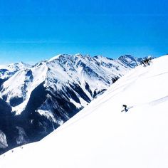 a man riding skis down the side of a snow covered slope on top of a mountain