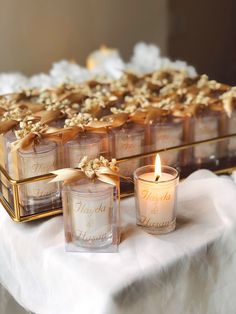 three candles are sitting on a table with gold ribbons and bows around the candle holders