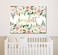 a baby's room with a white crib and pink flowers on the wall