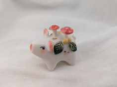 a white ceramic animal figurine with mushrooms and leaves on it's head