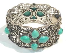 This beautiful vintage BJ   sterling silver hinged oblong shaped bangle  features a wide textured sterling filigree with bezel set with 12 pear shaped turquoise cabochon flower shapes on both sides.   The bracelet measures 7" inner circumference and 1.25" W and has a tongue and groove clasp and is in very good to excellent vintage condition with the turquoise nice, light tarnish.  Hallmarked BJ 925 China and weighs 58 grams Shipping prices vary on the weight of item. I do my best to keep shippin Turquoise Bangle For Formal Occasions, Formal Turquoise Bangle Jewelry, Bohemian Cabochon Jewelry For Formal Occasions, Formal Bohemian Jewelry With Cabochon, Formal Bohemian Cabochon Jewelry, Silver Cabochon Bracelet For Wedding, Elegant Turquoise Bangle For Formal Occasions, Wedding Silver Bracelet With Cabochon, Antique Turquoise Bangle