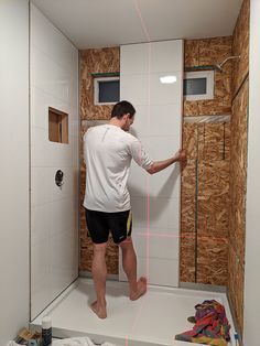 a man is standing in the shower with his feet up