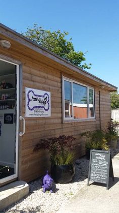 the outside of a dog grooming shop with its door open and sign in front