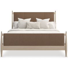 a bed with white pillows and brown headboard