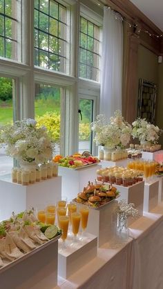 a buffet table filled with different types of food and drinks on display in front of large windows