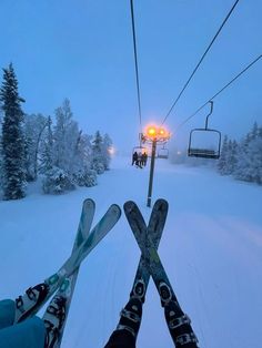 two skiers are standing in the snow under a ski lift