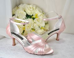 a pair of pink high heeled shoes next to flowers