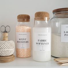 three jars with labels on them sitting on a shelf next to yarn, scissors and other items