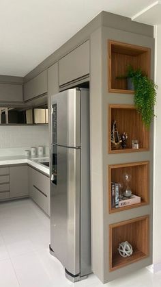 a modern kitchen with stainless steel appliances and wooden shelves on the wall, along with white tile flooring