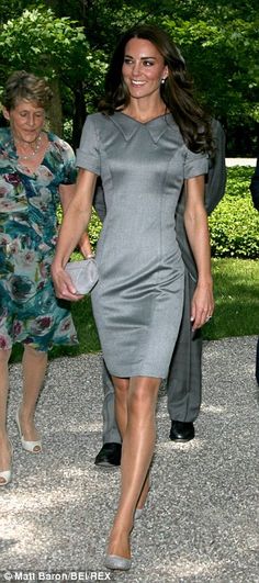 a woman in a gray dress is walking with two other women and one man behind her