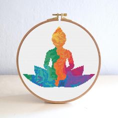 a cross stitch buddha sitting on a lotus flower