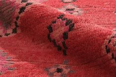 a red rug with black and pink designs on it's edges is laying on the floor