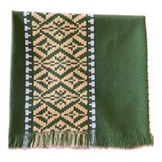 a green and beige blanket with fringes on it