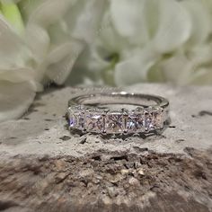 three stone diamond ring sitting on top of a piece of wood with flowers in the background