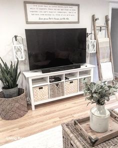 a flat screen tv sitting on top of a wooden stand in a living room next to wicker baskets