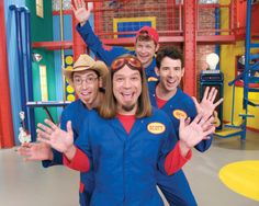 a group of men standing next to each other in front of a play room with toys