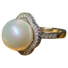 a pearl and diamond ring on a white background