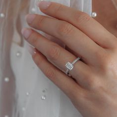 a woman's hand with a diamond ring on top of her finger and pearls around the band