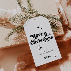 a merry christmas tag hanging from the side of a present box on top of a table