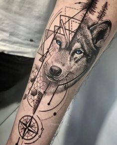 a man's arm with a wolf and compass tattoo on it