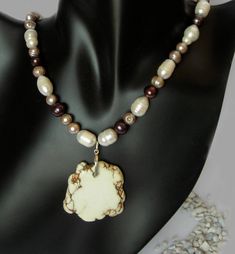 "I playfully named this necklace Pearl Bon-Bon because it reminds me of nougat and chocolatety treats - good enough to eat! It is designed with multi-coloured fresh water pearls of neutral hues - white, black, chocolate, taupe and silver.  The focal point is a large, natural, white Howlite pendant with a Sterling Silver bail.  A Sterling Silver Toggle Clasp finishes the look. Reversible. The pearl positions are not entirely symmetrical to add interest and a bit of whimsy. The necklace is approxi Brown Pearl Pendant Jewelry Gift, Handmade Brown Pearl Necklace Gift, Beige Pearl Necklace Gift, Brown Pearl Drop Jewelry Gift, Gift Brown Pearl Pendant Necklace, Brown Pearl Pendant Necklace Gift, Brown Pearl Drop Jewelry For Gift, Brown Pearl Pendant Necklace As Gift, Brown Pearl Pendant Necklace For Gift