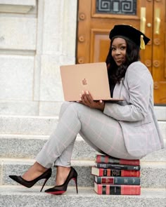 a woman is sitting on the steps with her laptop and books in front of her