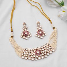 Embrace sophistication with this Kundan choker set, featuring delicate pearl lines and a charming pink floral center. Complete with exquisite dangler earrings, this set exudes elegance and is crafted with meticulous detail in mixed metal and 22kt gold plating. Finish: 22KT Gold Plating Material: Brass, Kundan,Pearls Color: Gold, White Size: Free Size, Adjustable Closure Type: Draw String Box Contains: 1 Necklace, 1 Pair Earrings Traditional Rose Gold Bridal Necklace For Festive Occasions, Elegant Pink Pearl Necklace For Festivals, Elegant Pink Meenakari Jewelry Sets, Traditional Pink Pearl Necklace For Celebration, Elegant Pink Kundan Necklace For Festivals, Elegant Pink Chandbali Bridal Necklace, Elegant Pink Meenakari Choker, Elegant Pink Meenakari Jewelry, Elegant Pink Bridal Necklace For Festivals