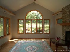 an empty living room with large windows and a rug on the floor in front of it