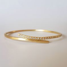 Handcrafted in 18 karat yellow gold and white diamonds, this bracelet is an elegant streak of gold, embracing your wrist. A wonderfully chic piece to add to any outfit, day or night. This feminine bracelet would make a very romantic gift. The thickness of the bracelet is 2X2 mm The inside diameter is 6 cm. If you need a different size, please contact me and let me know. :-: See more bracelets here: https://www.etsy.com/il-en/shop/OrnamentoStudio?ref=l2-shopheader-name&section_id=17248637 :-: Bangle Bracelets Gold Simple For Women, Gold Bracelet Simple, Diamond Bangle Bracelet, Diamond Bracelet Design, 18k Gold Bracelet, Unique Christmas Gift, Jewelry Bracelets Gold, Diamond Bangles Bracelet, Bangles Jewelry Designs