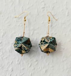 the earrings are decorated with green and yellow paper origami pieces, hanging from gold - plated earwires