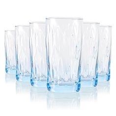 four clear glass tumblers are lined up in a row on a white surface with reflections