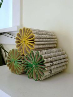 a stack of folded newspapers sitting on top of a white table next to a plant