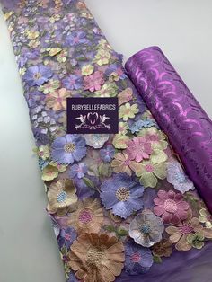 two rolls of purple and gold fabric with flowers on them, sitting next to each other