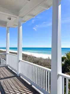 the porch is covered with white pillars and railings, overlooking the ocean on a sunny day