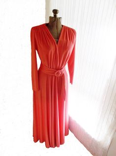 "This is a long sleeve maxi dress made by Bleeker Street. It is in the shade of a red coral. In different lighting this dress may look pink or reddish. It is a very light weight fabric that is smooth to the touch. It has a matching belt made with the same fabric that is pulled through a circular metal ring.  Measurements taken flat Shoulder to shoulder: armpit to armpit: 40\" inches (doubled) waist: 26\" inches (doubled) Waist to hem: open: 39.5 inches Shoulder to hem: 56\" inches Sleeve length: 21\" sleeve wrist: 3.5\" Union Made in USA 100% Polyester Imperfections: 3 minute pin holes. One on each side of the waist line. One on bottom part of dress near the right seem. In order to see them you would have to hold it up to the light. There are a few indentations on the fabric on the round p Maxi Robes, Union Made, Sleeve Maxi Dress, Long Sleeve Maxi, Metal Ring, Red Coral, Long Sleeve Maxi Dress, Dress Clothes For Women, Metal Rings