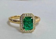 an emerald and diamond ring on a white surface