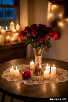 a vase filled with red roses sitting on top of a table next to lit candles