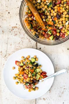 a white plate topped with a salad next to a bowl of chickpeas