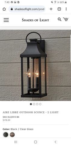 a black lantern hanging on the side of a wall with two lights attached to it